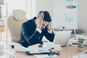 EWM-MFS-Projekt: Mann sitzt verzweifelt am Bürotisch und schlägt Hände vor sein Gesicht