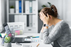 SAP-EWM-Projekt: Frau sitzt verzweifelt vorm Laptop und schlägt Hände vor ihr Gesicht